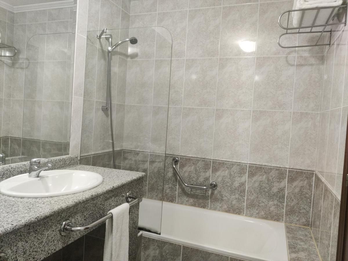 Bagno con lavandino, doccia e vasca, dotato di maniglie di sostegno.