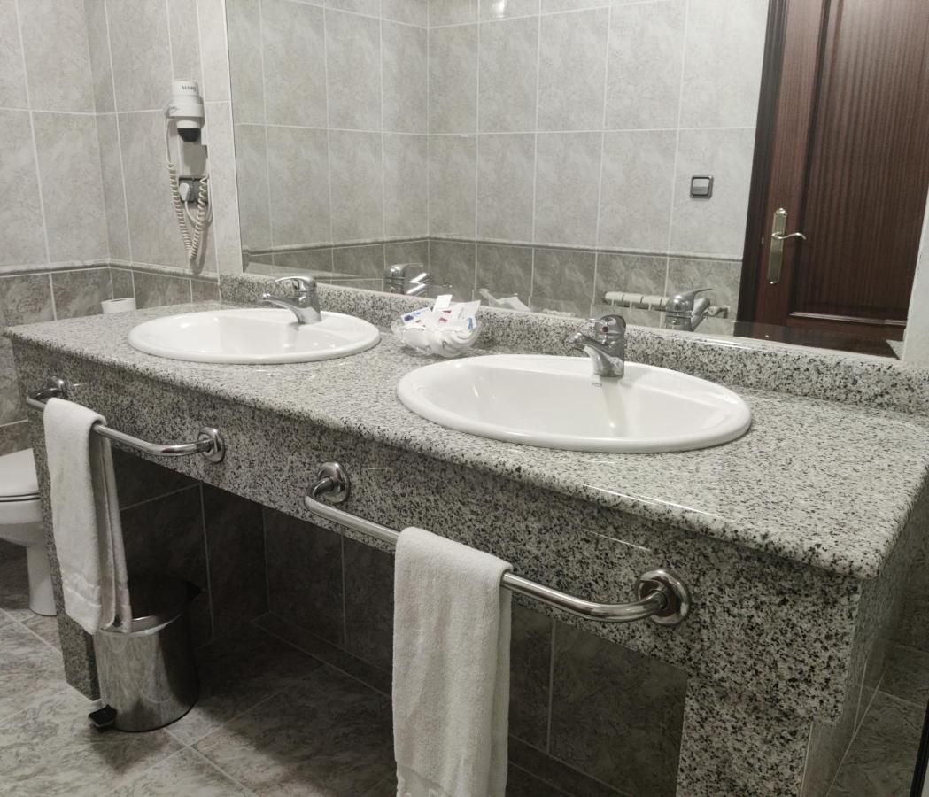 A bathroom with two sinks, a towel rack, and a hand dryer.