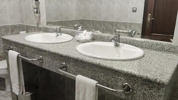 A bathroom with two sinks, a towel rack, and a hand dryer.
