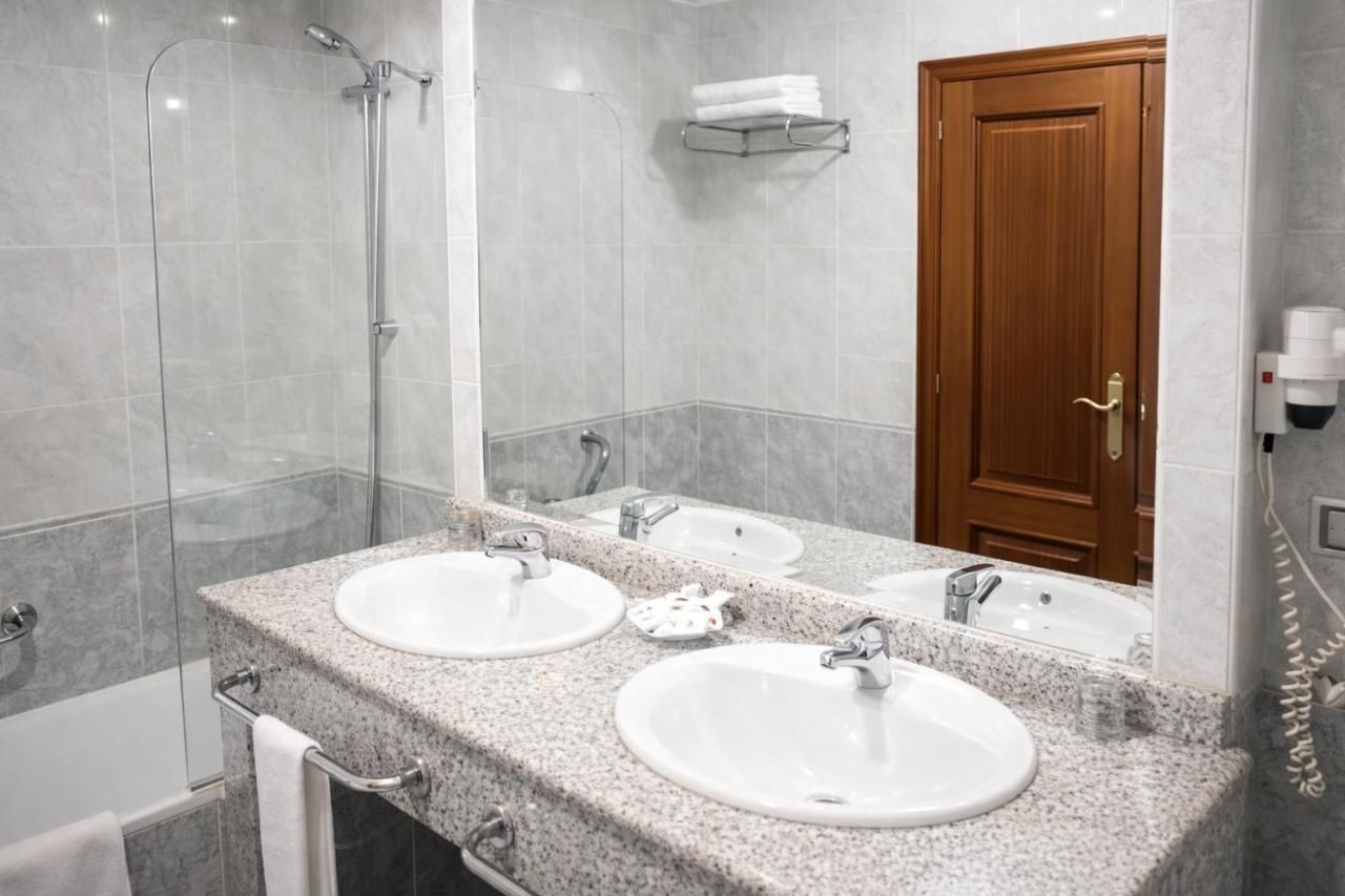 Un baño con dos lavamanos, una ducha y una puerta de madera.