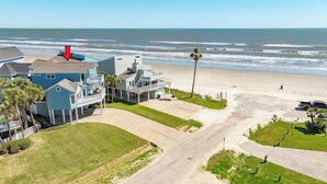 Une propriété située en bord de mer, comprenant une grande maison, une allée et une plage de sable.