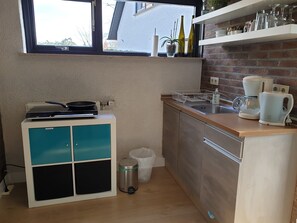 A compact kitchen with a built-in stove, a coffee maker, and a sink.