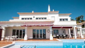 Um edifício de dois andares com piscina, área de estar ao ar livre e um pátio coberto.