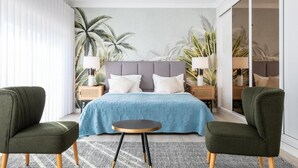 Quarto moderno com uma cama grande, duas mesas de cabeceira, duas luminárias e duas poltronas verdes.