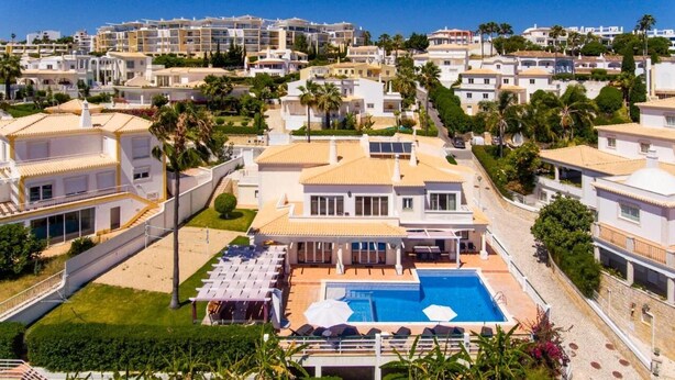 Um resort com piscina, espreguiçadeiras e vista para os edifícios ao redor.