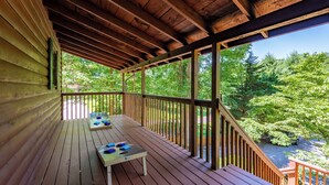 Um deck de madeira com mesa e cadeiras, com vista para uma área arborizada.