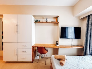 A modern bedroom with a bed, a desk, a chair, a TV, and a wardrobe. - A Modern Zen Hideaway (Iloilo)