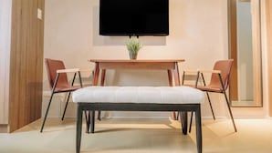 A modern room with a wooden table, two chairs, a bench, and a flat-screen TV mounted on the wall. - Your Ultimate Studio Escape (Iloilo)