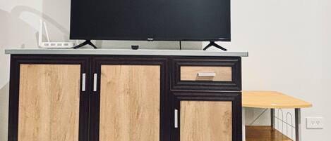 A wooden cabinet with a television on top, a small drawer, and a metal shelf below.