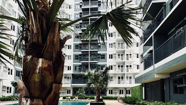 Un bâtiment moderne doté de nombreux balcons, d’une piscine et d’un jardin bien entretenu.