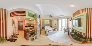 A modern hotel room with a curved ceiling, a large bed, a sitting area, a dining area, and a TV mounted on the wall. - A True Modern Sanctuary (Iloilo)