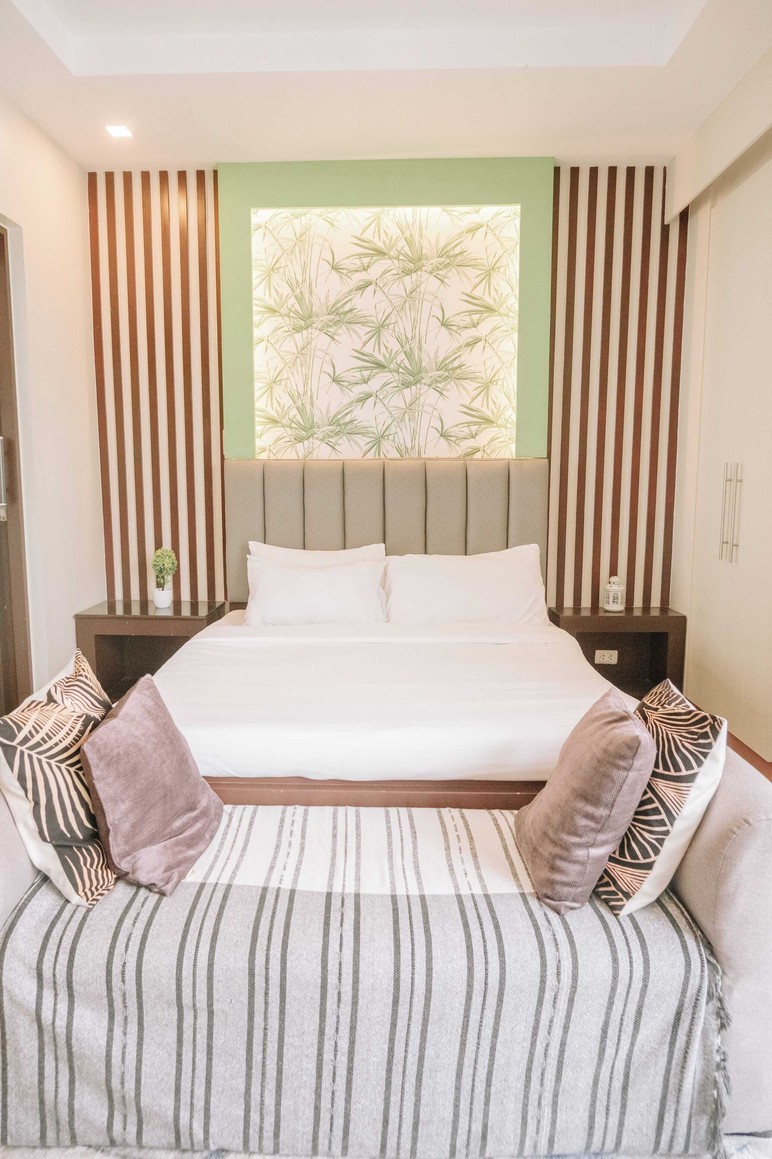 A modern bedroom with a large bed, striped cushions, a headboard with vertical lines, and a window with a bamboo pattern.