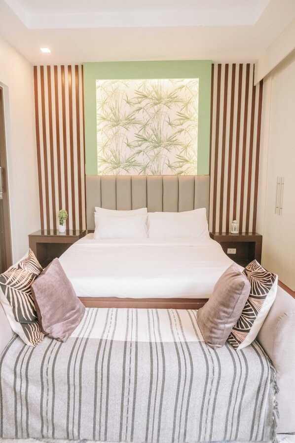 A modern bedroom with a large bed, striped cushions, a headboard with vertical lines, and a window with a bamboo pattern. - A True Modern Sanctuary (Iloilo)