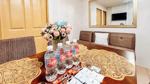 A dining area with a wooden table, bottles of mineral water, and food packets. - Cozy Family Suite Retreat (Iloilo)