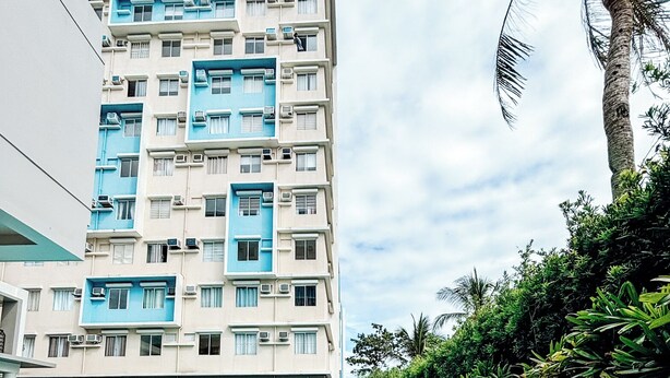 A swimming pool with a clear view of a multi-story building in the background. - Cozy Family Suite Retreat (Iloilo)