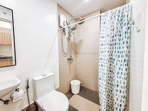A bathroom with a shower, toilet, and sink. - A Minimalist Urban Retreat (Iloilo)