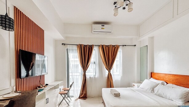 Une chambre d’hôtel moderne équipée d’un lit, d’un bureau, d’une chaise et d’un téléviseur.