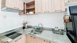 Une cuisine moderne avec des meubles en bois, un plan de travail en granit, une cuisinière encastrée et un four à micro-ondes.