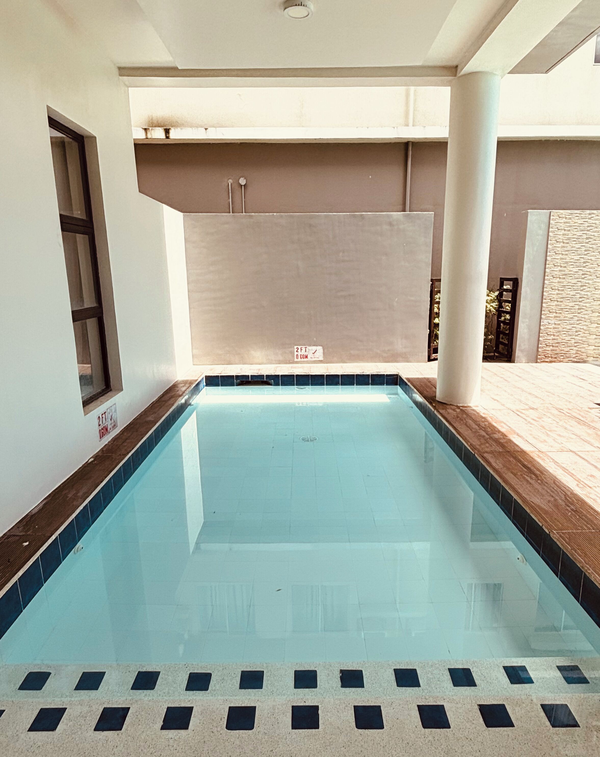 A swimming pool with a tiled edge and a wooden deck area.