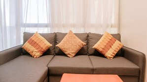 A sectional sofa with three patterned cushions and a matching ottoman. - Spacious & Cozy Urban Oasis (Iloilo)