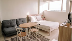 Un dormitorio pequeño con cama, sofá, mesita y escritorio con planta.