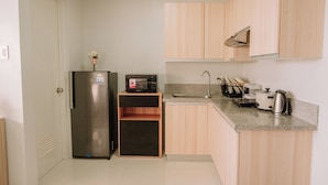 Una cocina compacta con refrigerador, microondas, lavadero y gabinetes de madera.