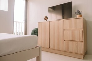 A bedroom with a bed, a wooden wardrobe, a flat-screen TV, and a small potted plant. - A Minimalist Cozy Escape (Iloilo)