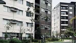 Ein modernes Apartmenthaus mit mehreren Balkonen, einem begrünten Innenhof und einem gepflasterten Weg.