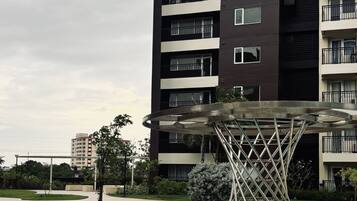 A modern apartment building with a swimming pool and a unique metal sculpture.