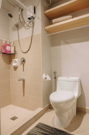 A bathroom with a shower, toilet, and a shelf with toiletries.