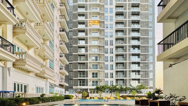 Un immeuble résidentiel de grande hauteur, avec une piscine en premier plan.