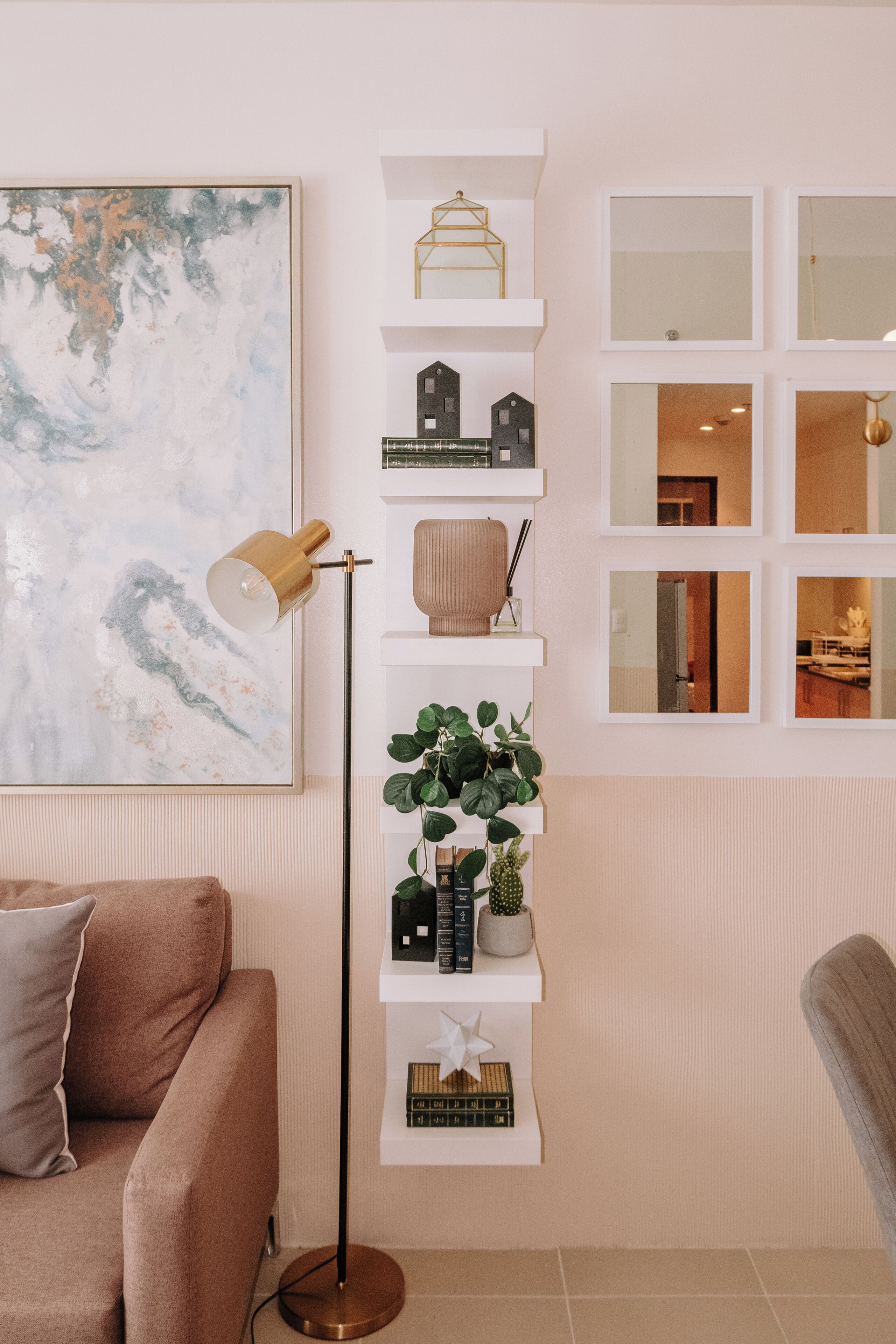 A modern living room with a sofa, a floor lamp, a bookshelf, and a large abstract painting.