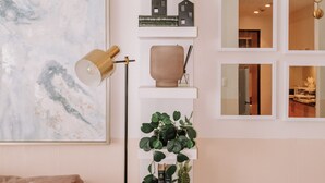 Un salon moderne avec un canapé, une lampe sur pied, une bibliothèque et un grand tableau abstrait.