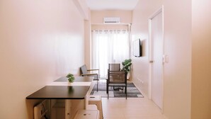 Ett kompakt bostadsutrymme med ett litet kök, en matplats och en sittgrupp.