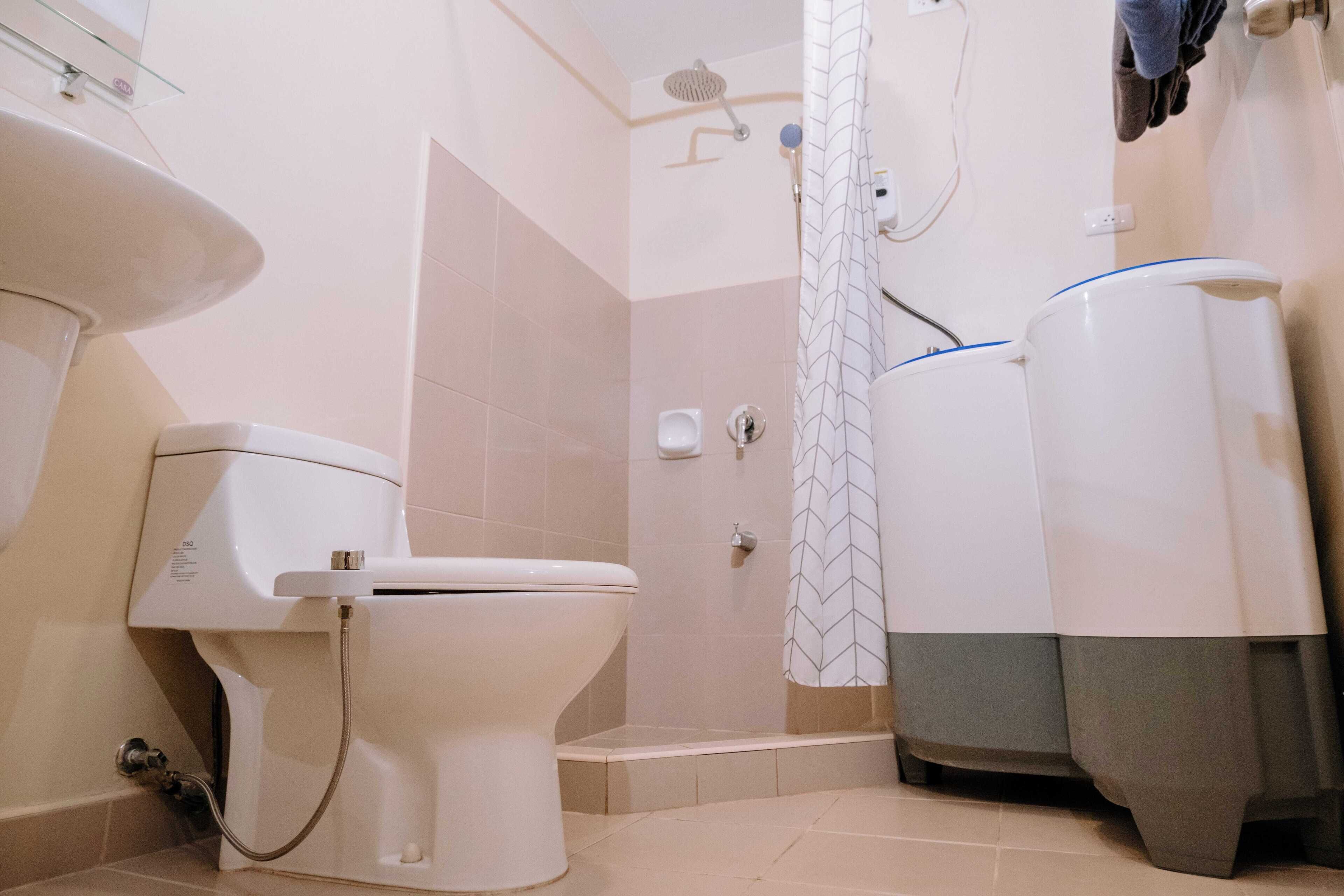 Un baño con inodoro, ducha y calentador de agua.