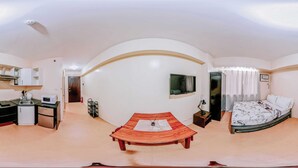 A compact, modern room with a kitchenette, a bed, a TV, and a small table. - Budget-friendly Comfy Nest (Iloilo)