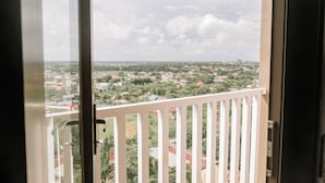 Un balcon doté d’une balustrade blanche, donnant sur un quartier résidentiel avec des maisons et de la verdure.