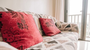 Un canapé recouvert d’un tissu à motifs géométriques, agrémenté de coussins à fleurs rouges.