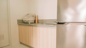 Une cuisine équipée d’un réfrigérateur en acier inoxydable, d’un plan de travail en granit et d’armoires en bois.