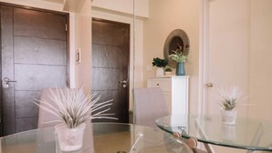 A room with a glass table, two chairs, a white cabinet, and two doors. - Simple Yet Stylish Escape (Iloilo)