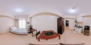 A compact living space with a bed, a dining table, a kitchenette, and an arched doorway. - Stylish & Affordable Comfort (Iloilo)