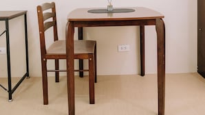 A room with a wooden table, a chair, and a small side table.