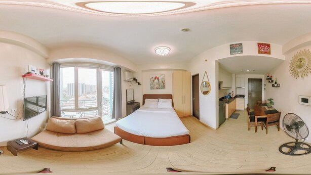 Une chambre d’hôtel moderne dotée d’un grand lit, d’un coin salon, d’une kitchenette et offrant une vue sur la ville.