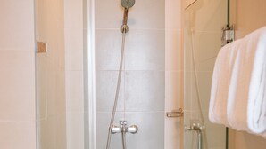 Un baño moderno con cabina de ducha de vidrio, inodoro y mampara de vidrio con toallero.
