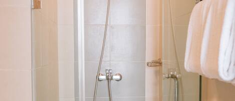A modern bathroom with a glass shower enclosure, a toilet, and a glass partition with a towel rack.