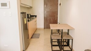 Una cocina compacta con una mesa y sillas de madera, un refrigerador y un microondas.