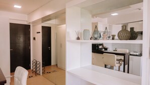 Una cocina moderna con armarios blancos, un comedor con una silla blanca y una puerta negra.