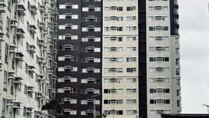 Un sendero conduce a un edificio residencial de varios pisos, con equipos de aire acondicionado y un suelo de baldosas de piedra.