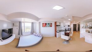 Un dormitorio moderno con una cama curvada, un televisor y una zona de escritorio.