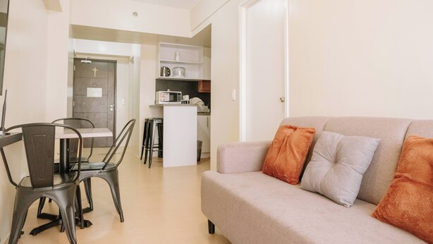 A modern apartment with a dining area, kitchenette, and a living room with a sofa and cushions. - Relaxing Sanctuary in Iloilo (Iloilo)